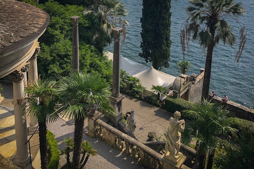 A landscaped garden with palm trees, statues, and a body of water. 3