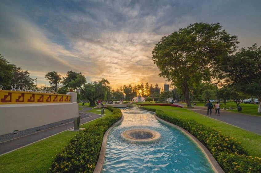 A park with a water feature, trees, and a sunset. 4