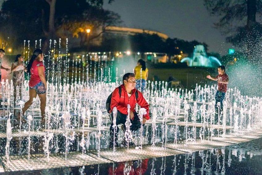 A water fountain display with multiple jets of water, illuminated by lights. 1
