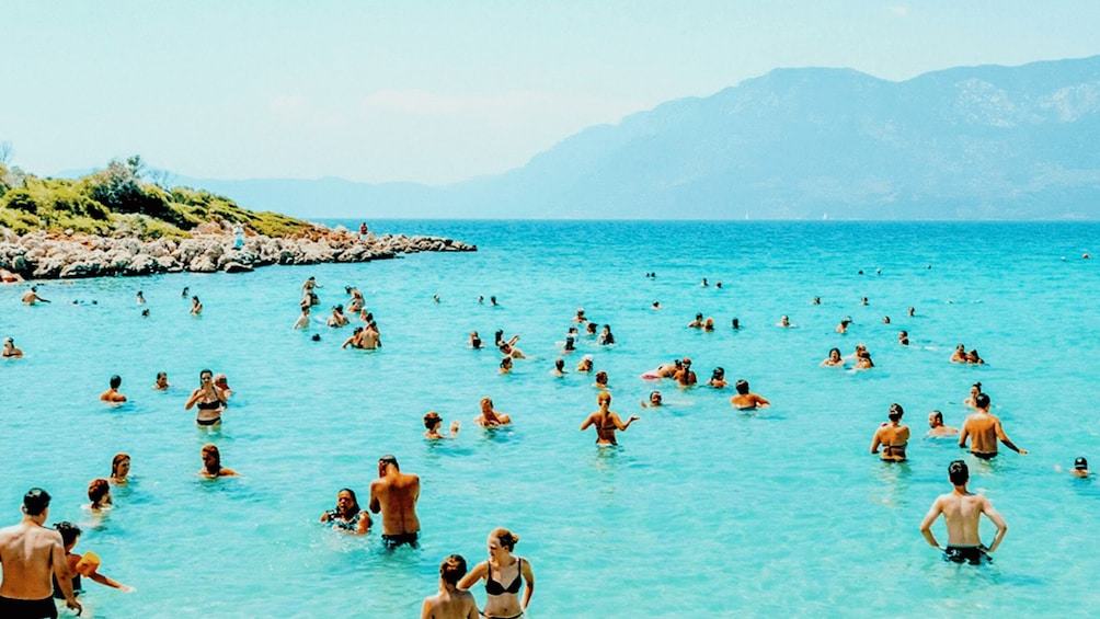 A crowded beach with people swimming and sunbathing. 4