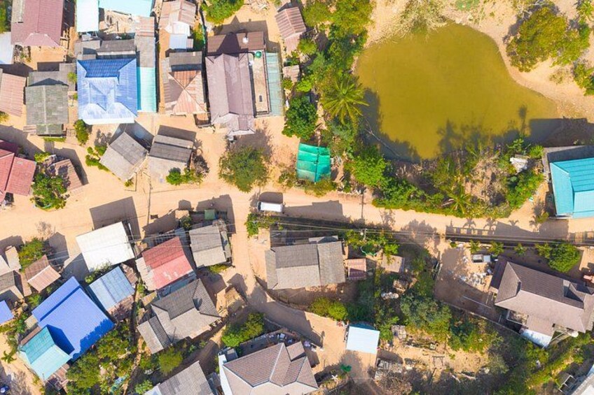 An aerial view of a residential area with houses, a small pond, and surrounding greenery. 2
