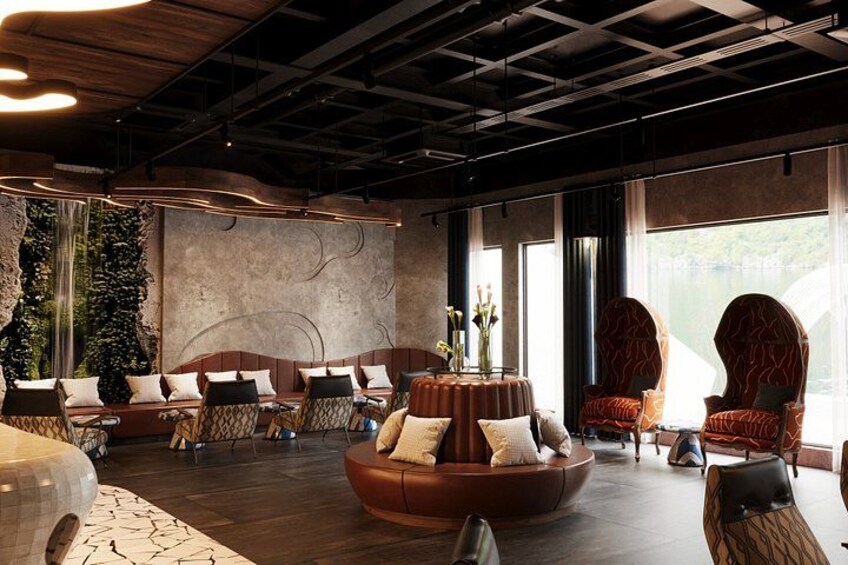 A modern lounge with leather sofas, a wooden ceiling, and large windows. 2