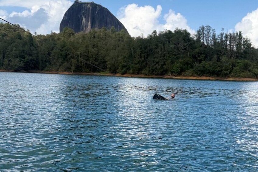Una persona nuota in un lago con una grande formazione rocciosa sullo sfondo. 3
