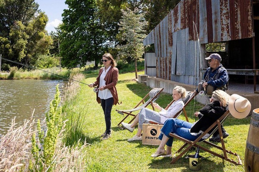 A group of people fishing by a lake, with a rustic building in the background. 5