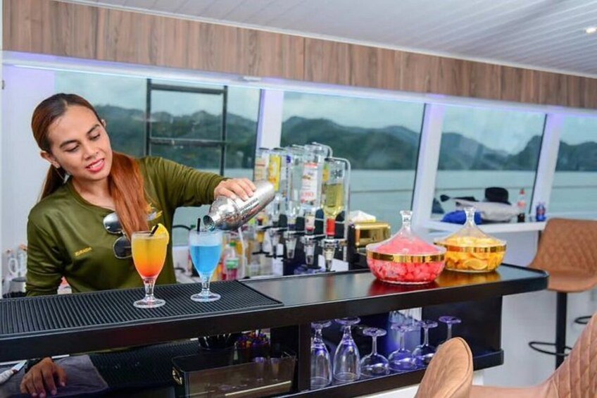 Un cantinero sirviendo bebidas en un bar con vistas panorámicas a montañas y un lago. 3