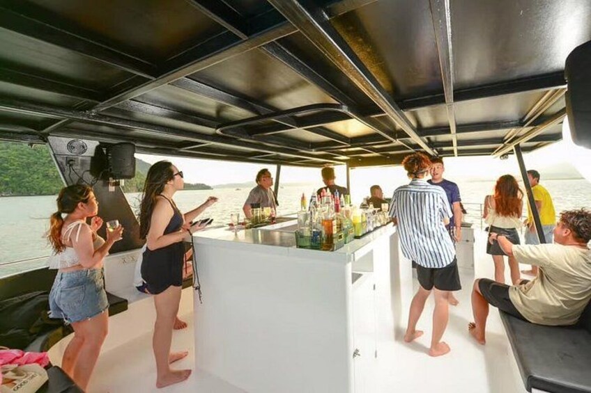 Un grupo de personas en un barco con zona de bar, rodeado de agua. 2