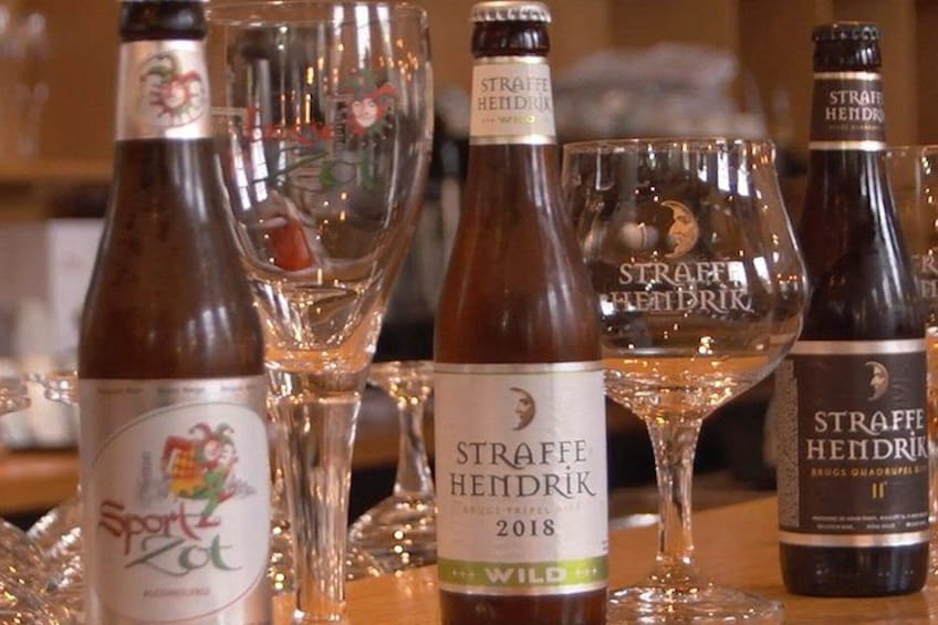 Flasker med Straffe Hendrik vin og vinglas på et bord. 1
