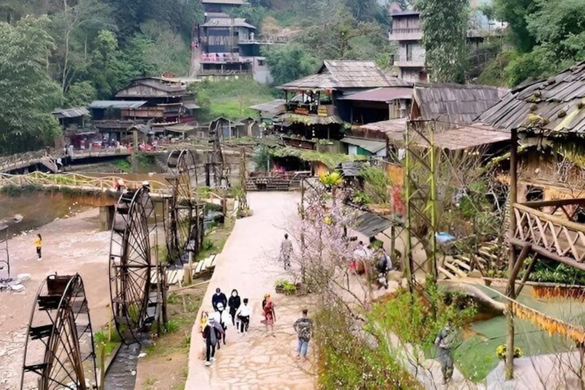 A village with traditional houses, a water wheel, and a bridge over a river. 5