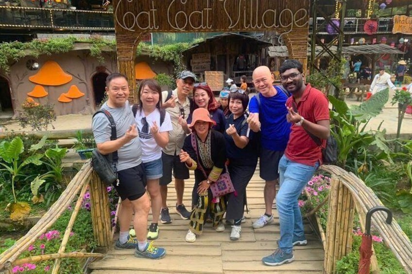 A group of people posing in front of a wooden archway with the text 'Coat Coat Village.' 3