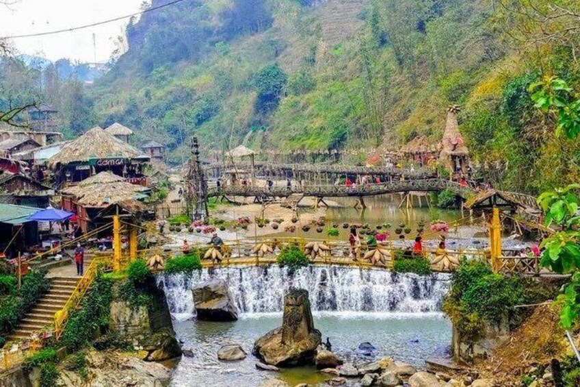 A waterfall, a bridge, and traditional huts in a mountainous area. 4