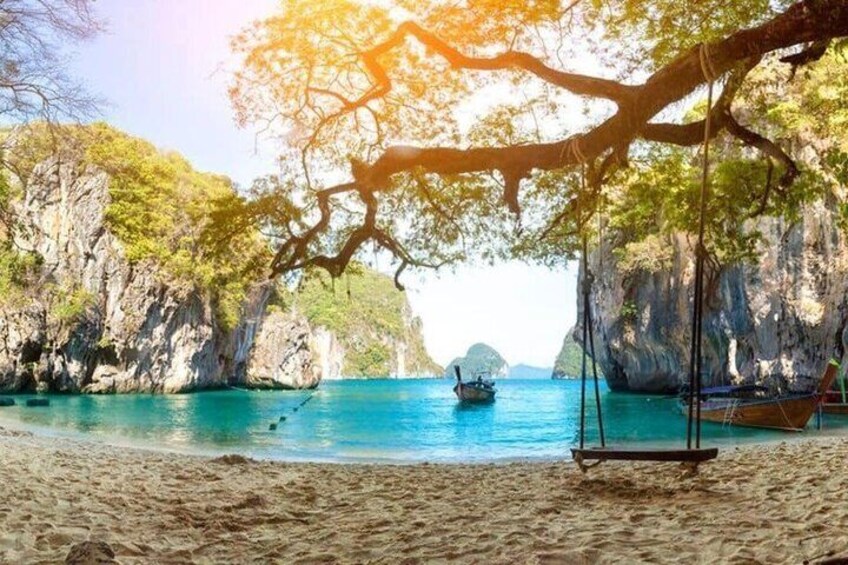 A beach with clear turquoise water, a swing chair, and a boat in the distance. 2
