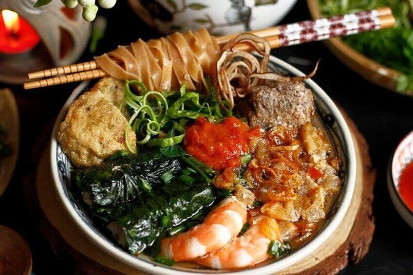 A bowl of Asian cuisine with various ingredients like shrimp, vegetables, and noodles. 1