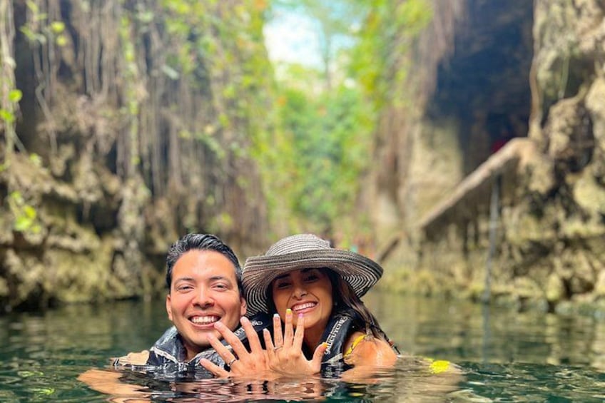 Two people in a water body surrounded by dense vegetation and rocky cliffs. 1