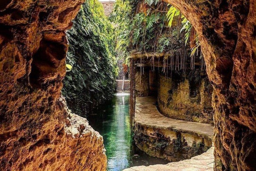 A natural rock formation with a water channel and steps leading to a small waterfall. 2
