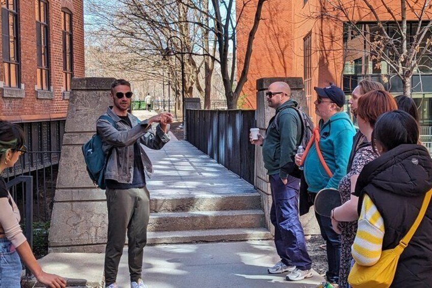 A person gesturing to a group of people on a city sidewalk. 5