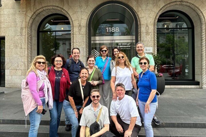 A group of people posing in front of a building with arched windows and a sign displaying '1188'. 3