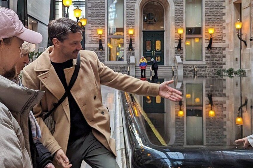 A person gesturing on a street with a building and street lamps in the background. 1