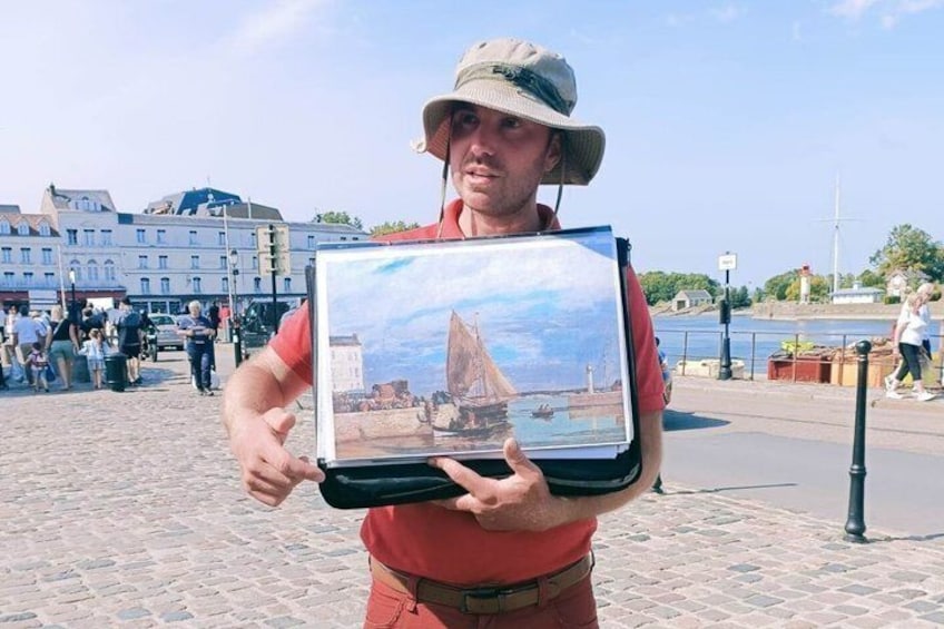 En person som håller i ett inramat fotografi av en segelbåt. 2