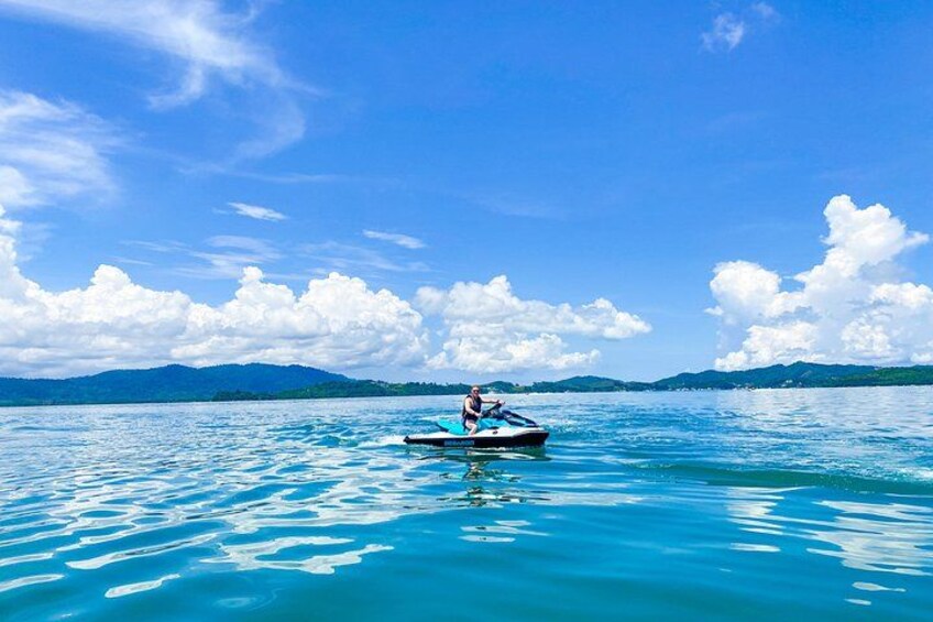 A person jet-skiing on a calm lake with mountains in the background. 5