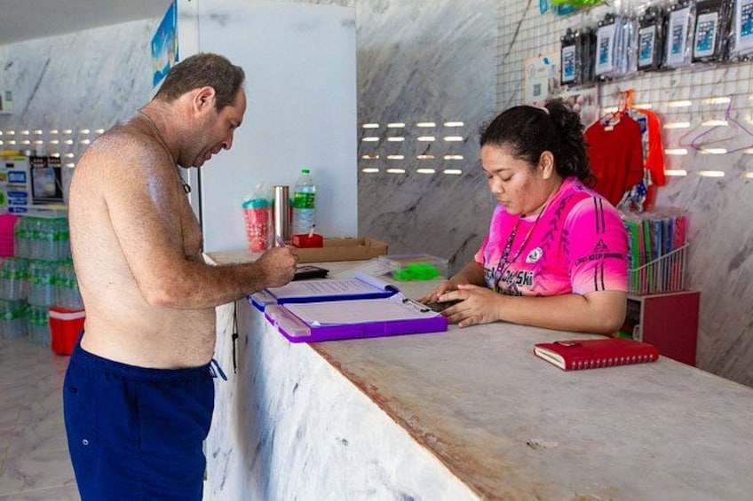 A man and a woman at a counter with a white marble background, a red shirt, and a purple folder. 2