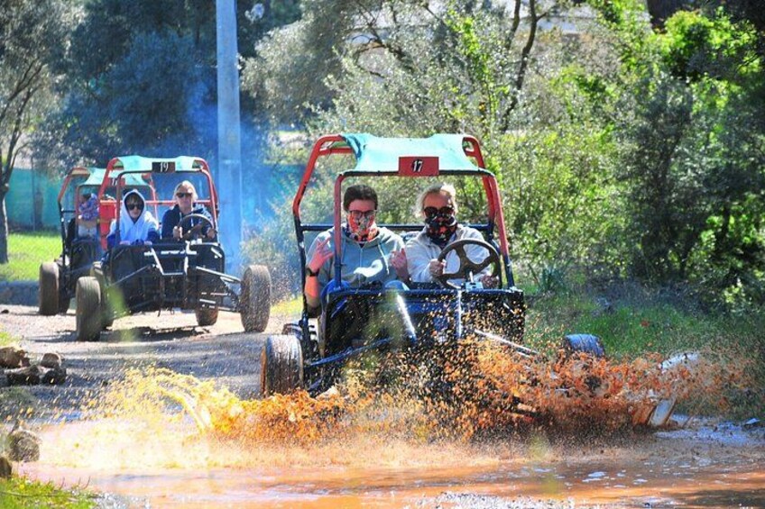 Tre personer i gokarts der kører på en vej, hvor vand sprøjter til alle sider. 2