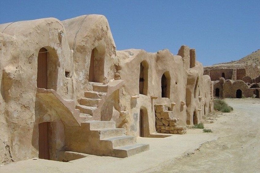 A series of ancient, arched doorways and staircases carved into a rock face. 4