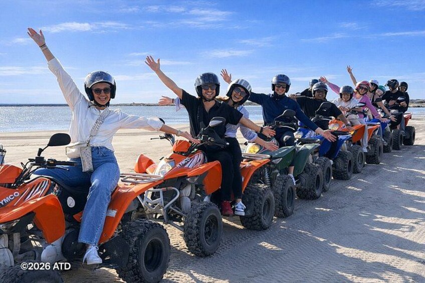 Un groupe de personnes à bord de quads s’est aligné sur une plage. 2