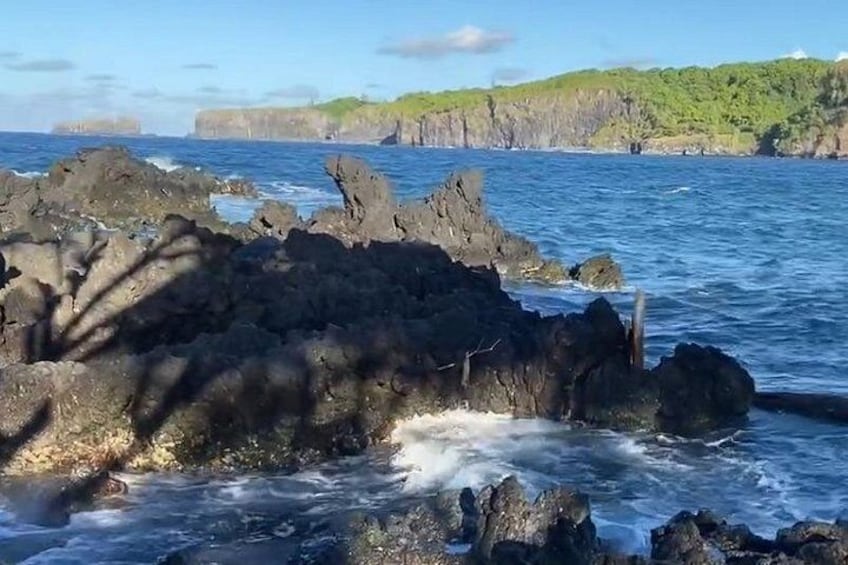 Côte rocheuse, vagues de l’océan et collines verdoyantes à l’horizon. 2