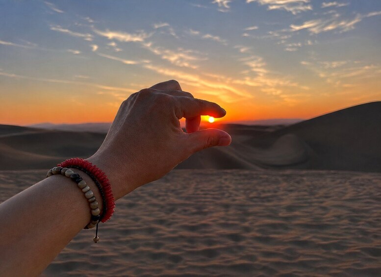 A hand holding a sun with a desert landscape in the background. 2