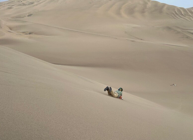 A person lying on a sand dune in a desert landscape. 3