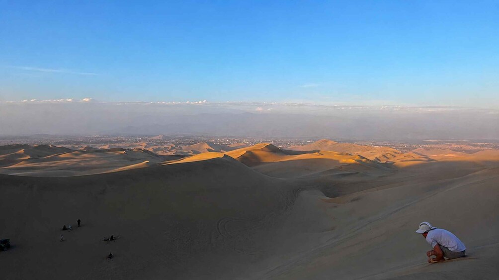 A desert landscape with sand dunes and a person sitting on the sand. 4
