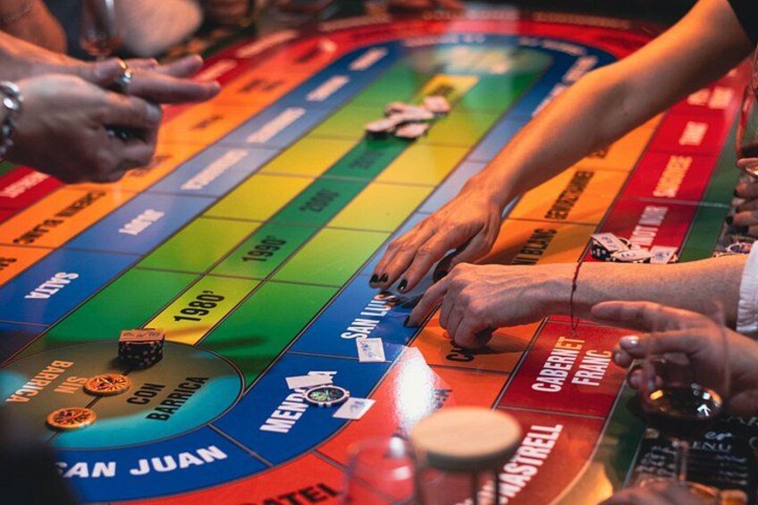 A board game with colorful tiles and players' hands. 1