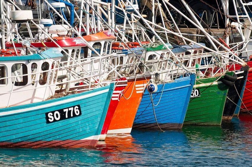 A row of colorful fishing boats docked at a marina. 2