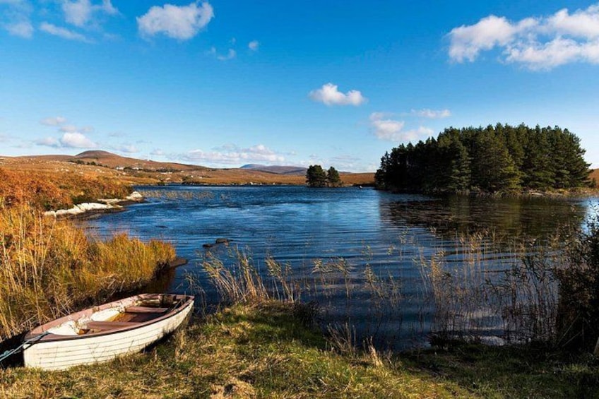 A calm lake with a small boat, grassy banks, and a forested island. 5