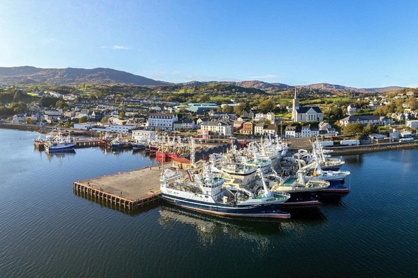 A harbor with boats docked, a pier, and a town in the background. 4