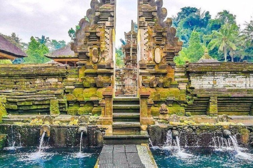 A traditional Balinese water temple with stone carvings and a central water feature. 2