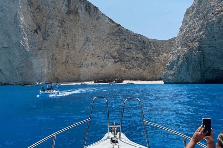 A boat in a clear blue sea with rocky cliffs in the background. 3