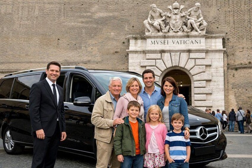 Una familia posando frente al edificio MVSEI VATICANI con un coche negro. 1