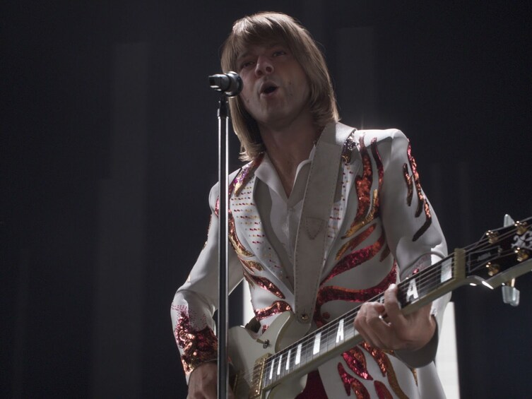 A person playing an electric guitar on stage. 5