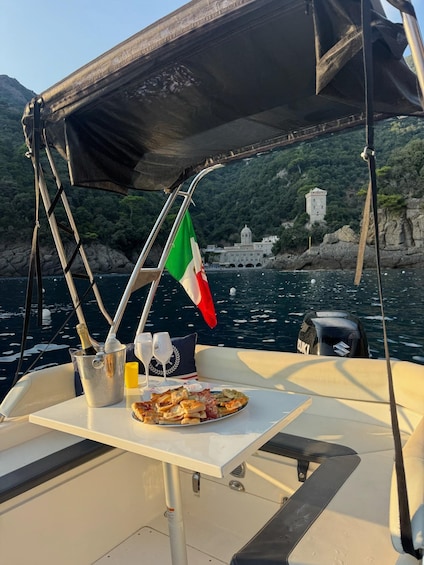 A boat with a table set for a meal, a flag, and a coastal landscape with a building. 1