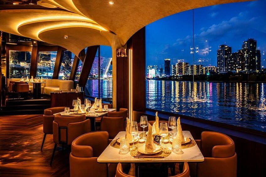 Een restaurant met gedekte tafels, uitzicht op de skyline van de stad en een ligging aan het water. 3