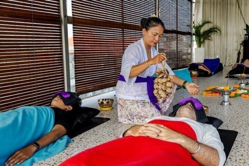 A person lying on a mat receiving a massage from a practitioner. 1