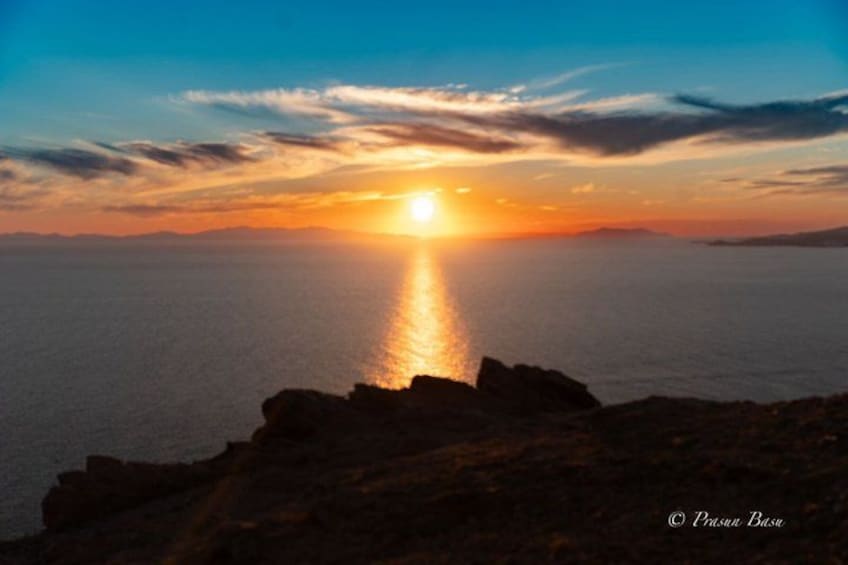 A sunset over a calm sea with rocky coastline. 4