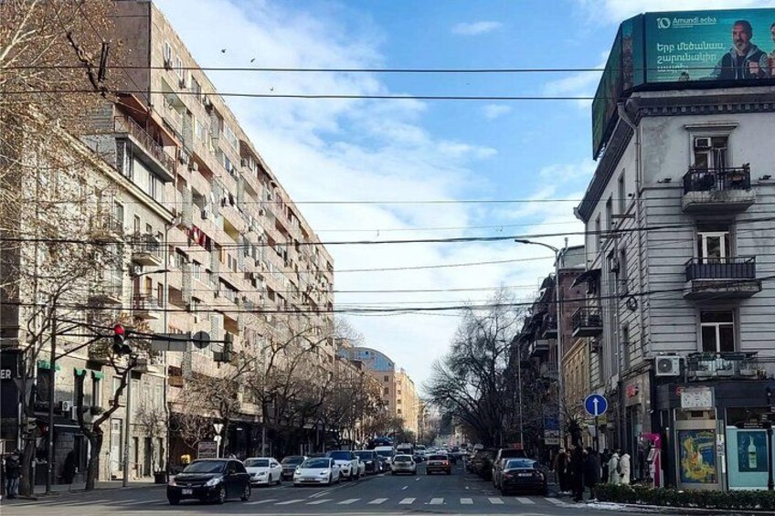 A city street with multi-story buildings, cars, and pedestrians. 5