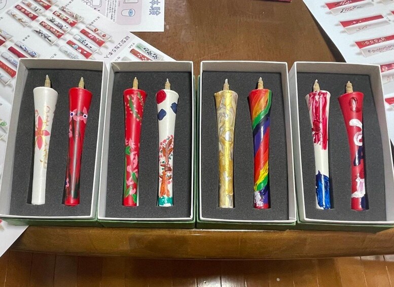Four boxes of colorful candles with floral and abstract designs. 1