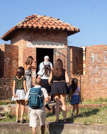 A group of people approaching a brick building with a tiled roof. 4