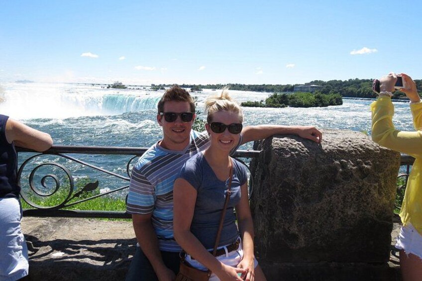 A couple sitting by a railing with a waterfall in the background. 2