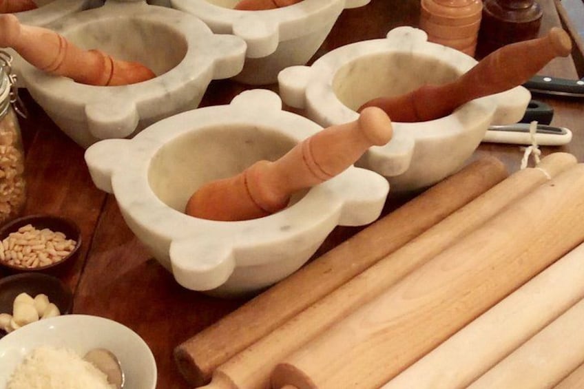 A kitchen with stone mortar and pestle sets, wooden rolling pins, and bowls of grains. 1