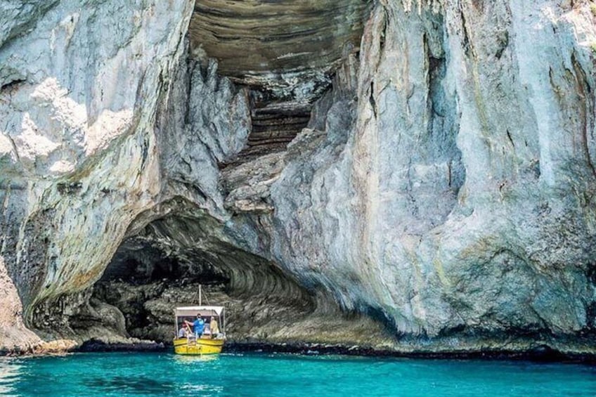A boat navigating through a natural rock formation with a cave entrance. 5