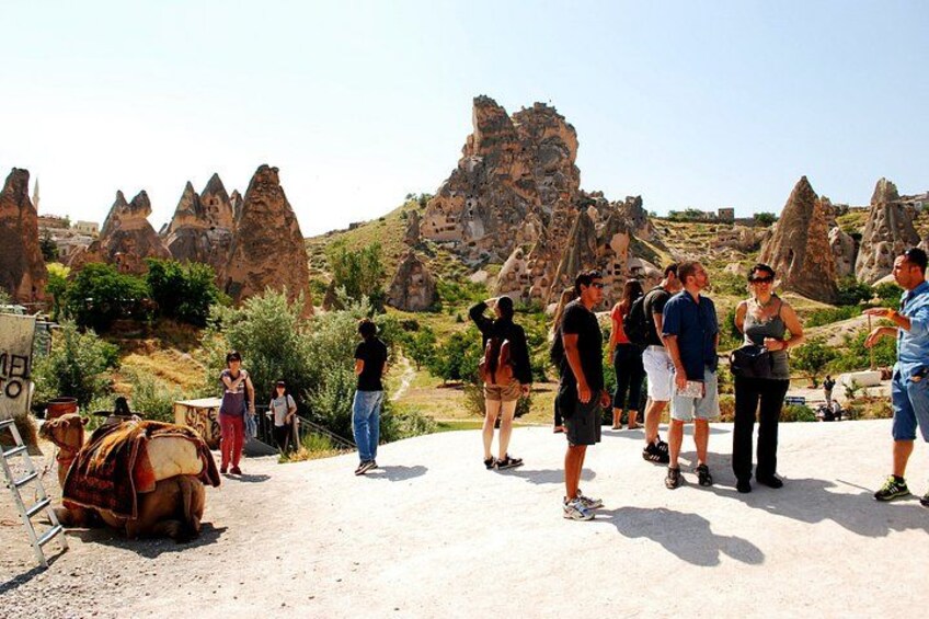A group of people standing on a dirt path with rock formations in the background. 1